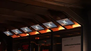 Modern ceiling installation featuring multiple rectangular backlit panels with white illuminated logos and warm orange uplighting along the edges.