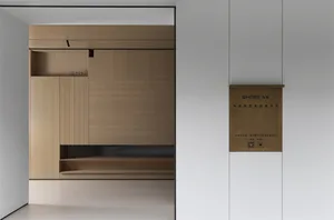 Modern minimalist entryway featuring a light oak built-in cabinet with open shelves and hidden storage against a white wall.