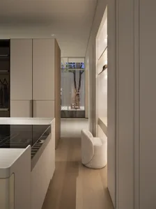 Modern minimalist walk-in closet featuring built-in beige cabinetry, light oak flooring, a textured boucle swivel chair, and a view to a courtyard with trees.
