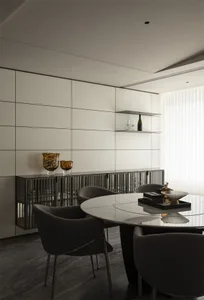 Modern minimalist dining room featuring a round marble dining table, dark upholstered dining chairs, and a black metal slatted sideboard against a white grid wall.