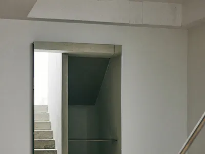 View of a minimalist concrete staircase and hallway with exposed concrete walls and floor in a modern interior.