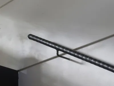 安裝在白色磁磚牆角的黑色皮革包覆金屬扶手，配有獨特的U型金屬支架。