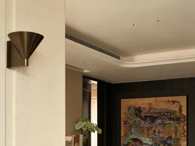 Modern entryway featuring a dark wood upright piano, a large abstract painting, a wooden chair, and a potted plant under warm lighting.