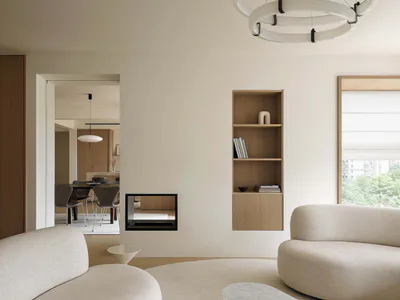 Modern minimalist living room featuring two curved cream boucle sofas, a marble coffee table, built-in oak shelving, and a large circular chandelier.