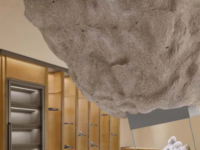 Modern mineral gallery interior featuring a massive floating raw stone boulder installation, illuminated display shelves with mineral specimens, and a glass display case with a large quartz cluster.