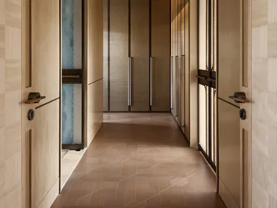 Long, narrow minimalist hallway featuring light oak wood paneling, textured cabinet doors, geometric patterned floor tiles, and warm ambient lighting.