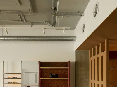 現代精品店室內空間，粉色邊框軟木展示架、混凝土地板、裸露天花板管線與配件展示單元。