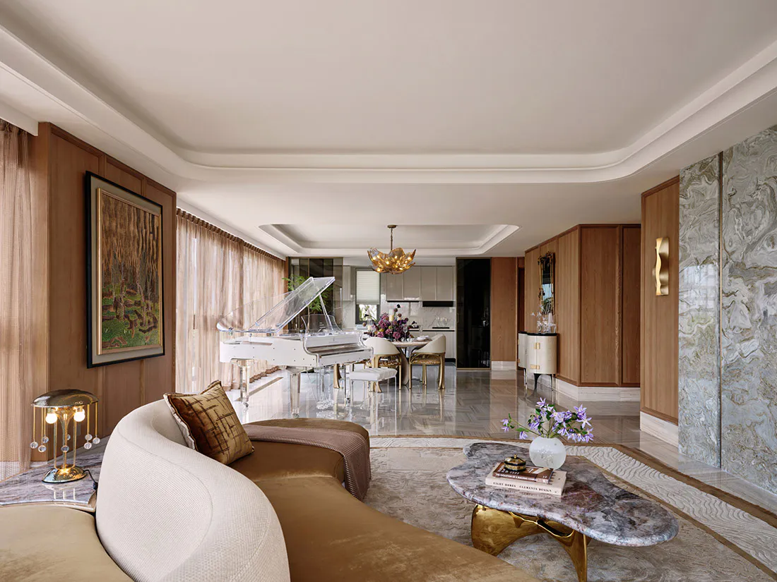 Luxurious open-plan living room with a white grand piano, curved cream sofa, marble coffee table, walnut wood paneling, and marble accent wall.