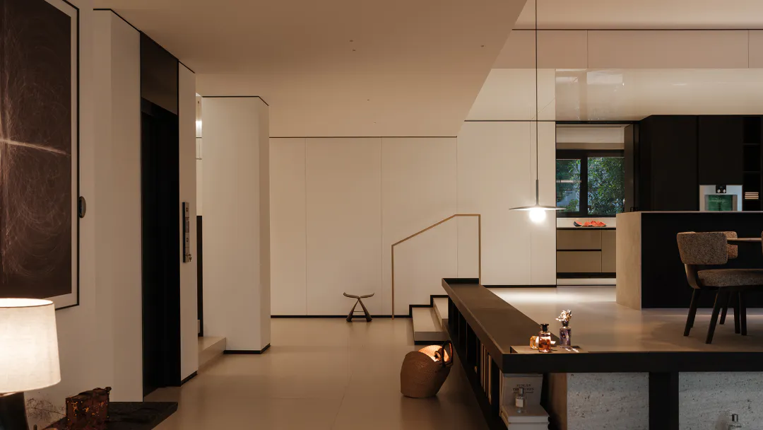 Modern minimalist open-plan interior featuring concrete island, floating staircase, pendant light, and neutral color palette.