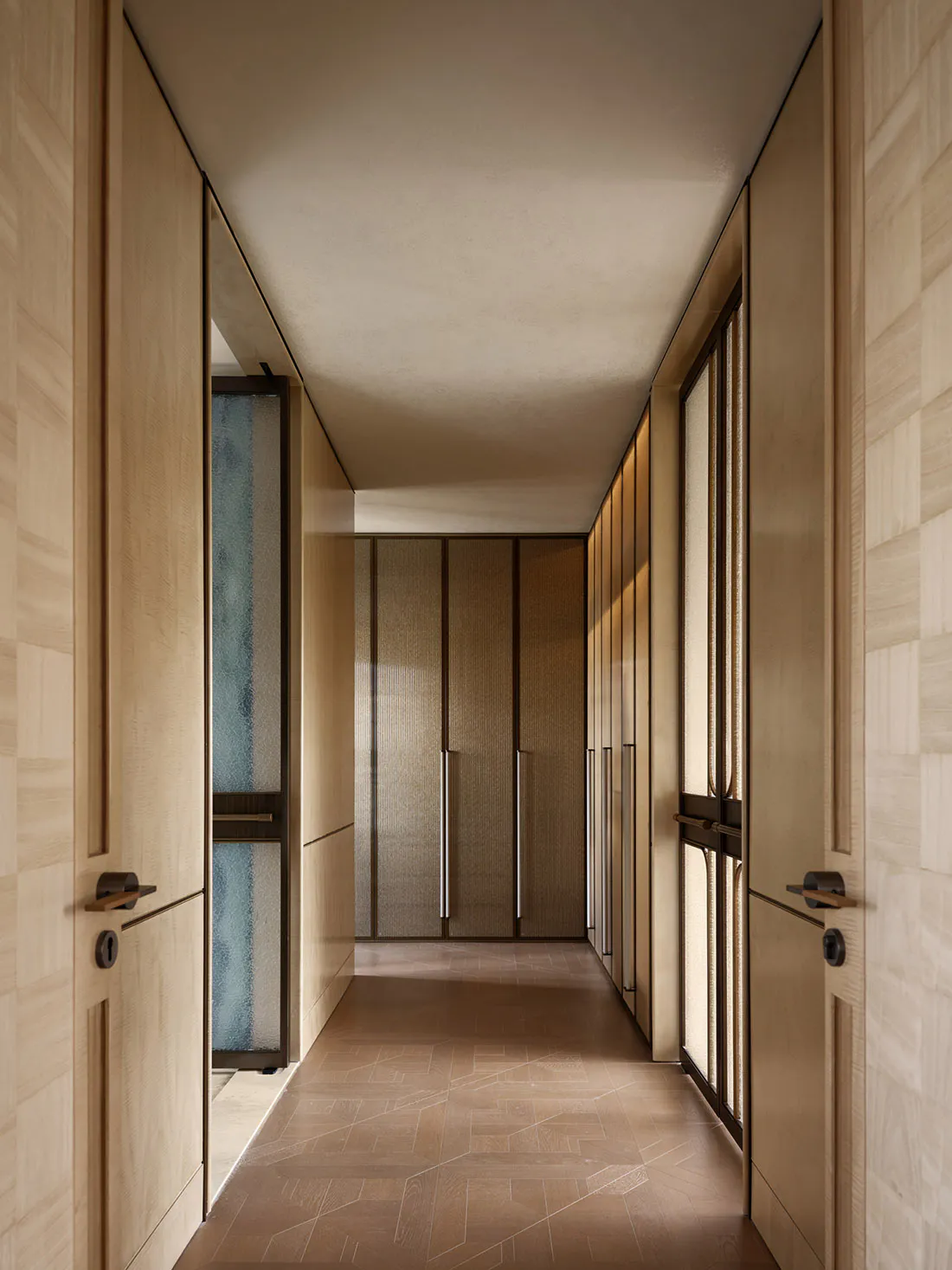 Long, narrow minimalist hallway featuring light oak wood paneling, textured cabinet doors, geometric patterned floor tiles, and warm ambient lighting.