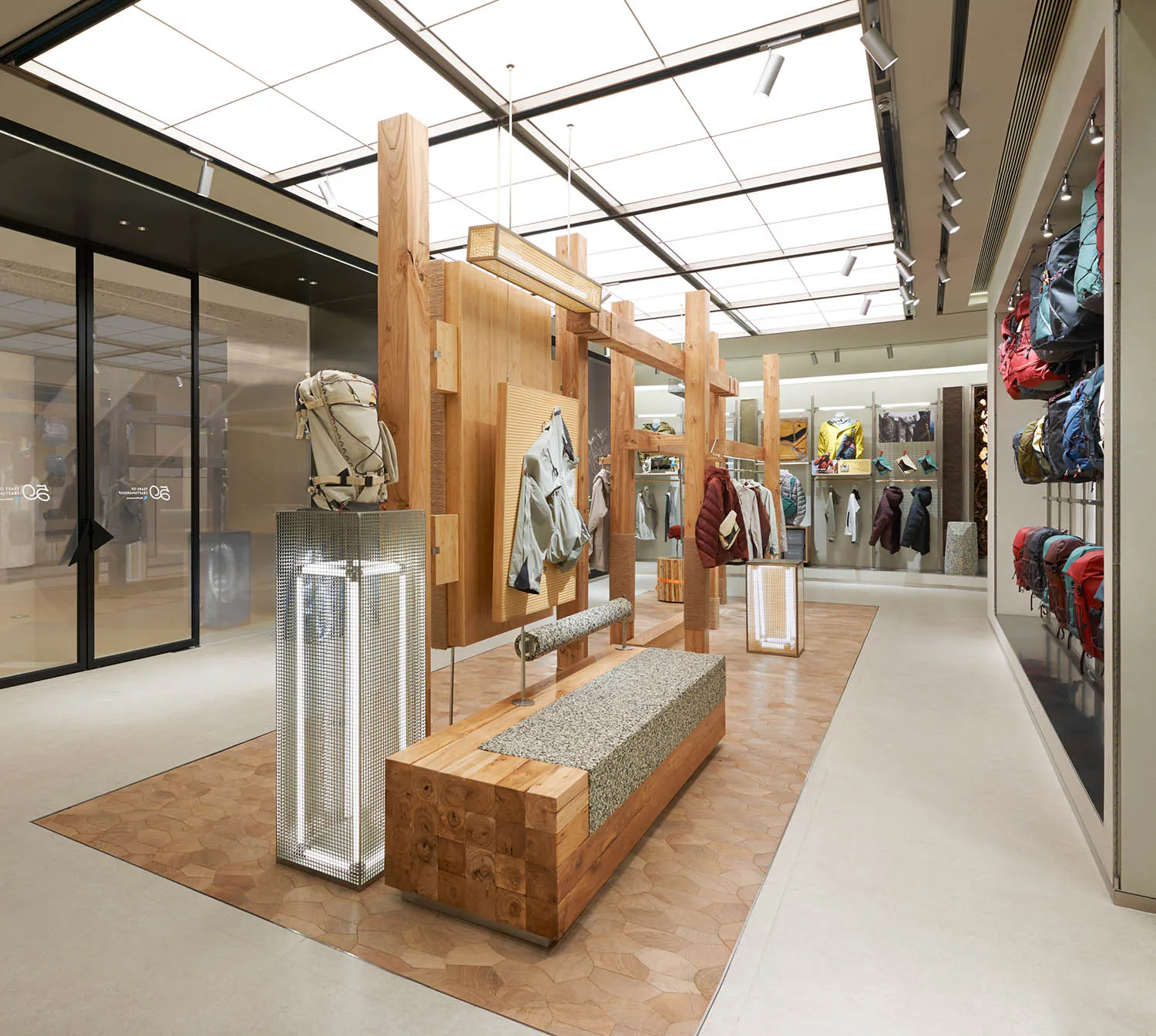 Patagonia 現代零售店內部,大型橡木展示結構、水磨石桌面木長椅、金屬網燈柱,以及在天窗下展示的戶外裝備。