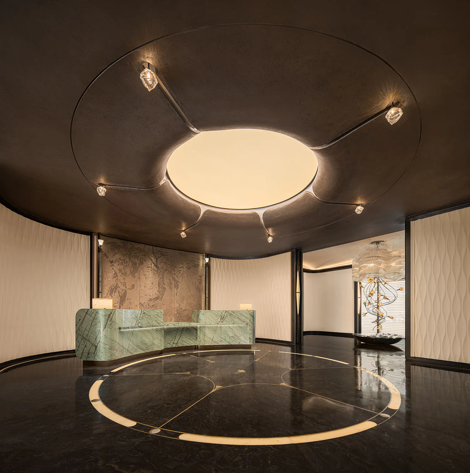Luxurious hotel lobby featuring a curved green marble reception desk, dark reflective marble floor with gold inlay, and a dramatic circular ceiling fixture with integrated lighting and crystal accents.