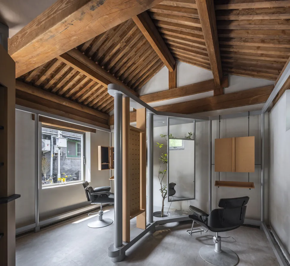 Modern industrial minimalist hair salon interior featuring exposed wooden ceiling beams, polished concrete floor, black leather salon chairs, and a mix of metal and wood partitions.