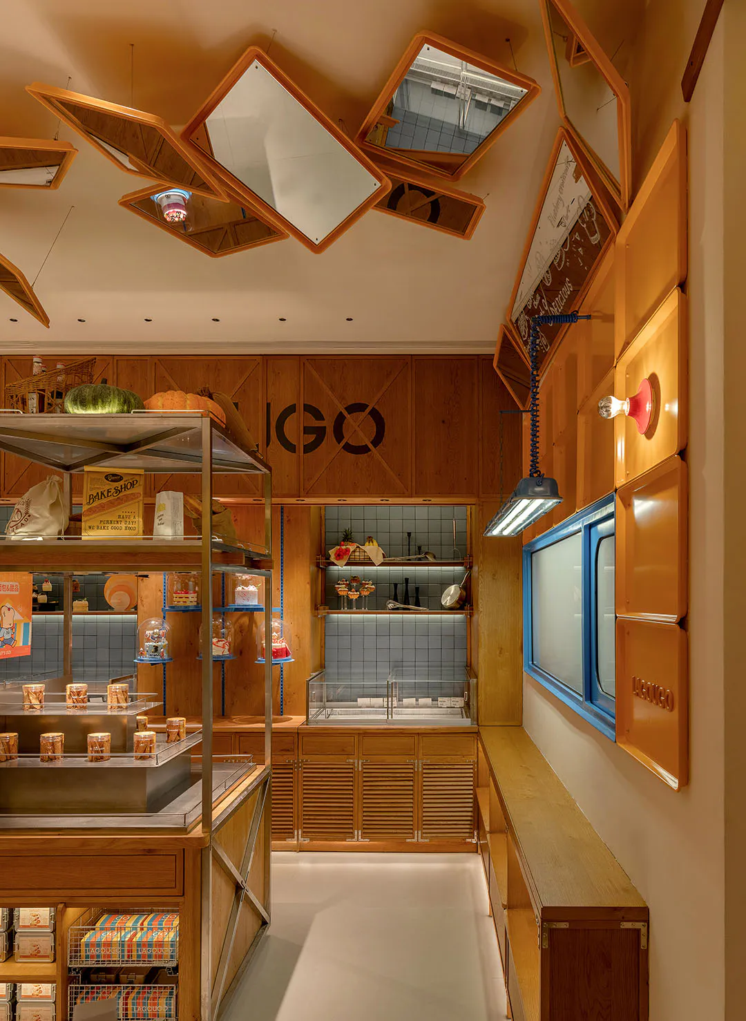 Lugo 麵包店內部空間,展示暖色木質櫃體、玻璃甜點展示櫃、色彩豐富的商品包裝,以及天花板上獨特的斜角木框鏡面裝置。