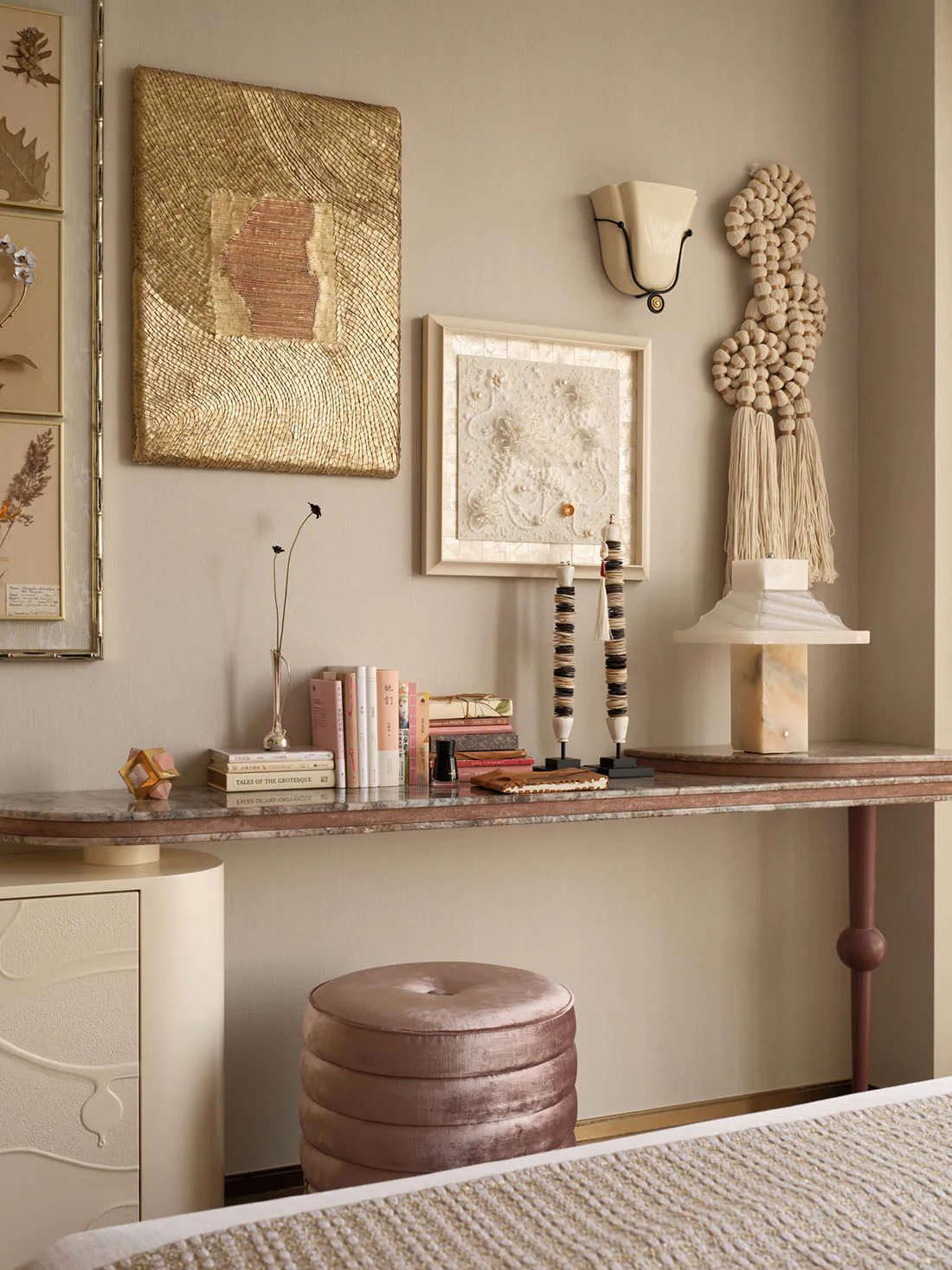 Elegant console table styled with textured gold and white wall art, marble lamp, velvet stool, and curated books against a neutral wall.