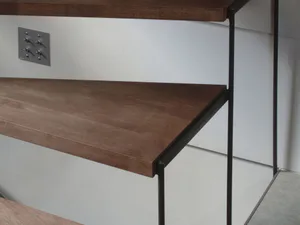 Close-up view of a modern two-tier console table made of walnut wood with a black metal frame, mounted against a white wall with a metallic control panel featuring multiple switches.
