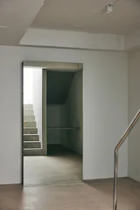 View of a minimalist concrete staircase and hallway with exposed concrete walls and floor in a modern interior.
