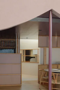 Modern dining area featuring pastel pink ceiling, mauve and natural wood cabinetry, wooden wishbone chairs, and a pass-through window to the kitchen.