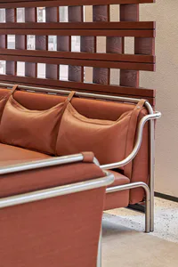Modern cognac leather sofa with chrome tubular frame and wooden slat privacy screen in a commercial interior space