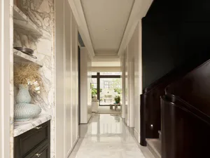 Elegant long hallway with white marble floors and walls, built-in marble shelving with decorative vases, dark wood staircase, and view to a bright living area.