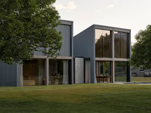 Modern two-part house with dark corrugated metal cladding, large glass windows reflecting mountains and trees, open interior showing living and dining areas, set on a green lawn with mature trees.