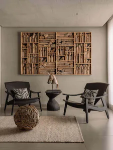 Modern minimalist living room featuring a large wooden grid display filled with hundreds of driftwood sculptures and figures, two dark wooden armchairs with patterned cushions, a horse head sculpture on a black pedestal table, and a woven spherical driftwood stool on a natural jute rug.