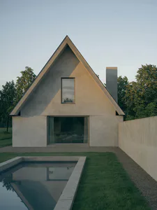 Modern triangular concrete house with a large gable roof, floor-to-ceiling glass windows, and a rectangular reflecting pool in the foreground surrounded by lawn and trees.