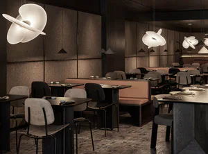 Modern Japanese restaurant interior with dark textured walls, warm wood tables, upholstered chairs, and large sculptural white pendant lights creating a moody elegant atmosphere.
