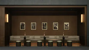 Modern lounge with dark wood paneled walls, linear wall sconces, upholstered bench seating, round black tables with candles, and framed black and white photographs of athletes including tennis, baseball, and hockey players.