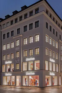 Evening view of a multi-story MaxMara flagship store on a corner building with illuminated windows and elegant stone facade