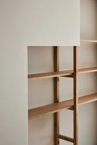 Close-up view of a minimalist built-in shelving unit made from light-colored solid wood set into a white wall niche.