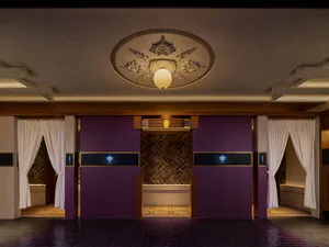 Modern Japanese-style entrance hall featuring rich purple cabinetry, white noren curtains, dark tiled floor, and an ornate circular plaster ceiling medallion with a hanging pendant light.
