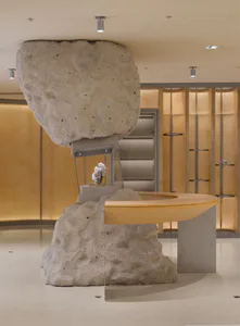 現代礦物展覽館接待台，上方有巨大的懸浮天然岩石裝置，背景為燈光照明的展示櫃。
