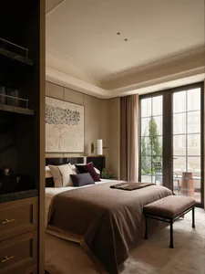 Modern luxury bedroom with taupe wool throw blanket, layered neutral pillows, dark wood headboard, large botanical wall art, and a upholstered bench at the foot of the bed.