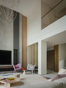 Modern luxury living room with high ceiling, marble coffee tables, pink and patterned accent chairs, large chandelier, and double-height balcony.