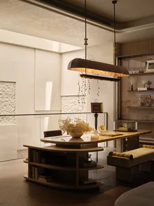 Modern home office featuring a large curved travertine desk with integrated shelving, a sculptural two-tier pendant light with hanging crystals, a textured stone wall, and built-in wooden shelving displaying decorative objects.