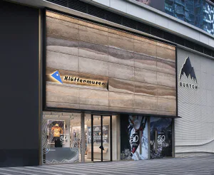 Klattermusen 與 Burton 聯名台北店外觀，大型立面由層次分明的米色與棕色洞石組成，搭配發光品牌標誌。
