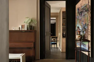 Elegant interior hallway with a walnut upright piano, potted plant, large abstract painting, and dark wood console table leading to a dining area.