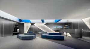 Modern corporate lobby interior with blue modular sofas, geometric lighting features, and a large illuminated INNOVISION logo on a dark wall with circuit board patterns.