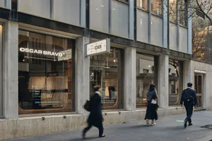 現代極簡風格零售店面，白色大理石柱、大面積玻璃櫥窗，以及街道層的 Oscar Bravo 發光招牌。
