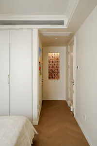 Modern minimalist bedroom hallway featuring white built-in wardrobe, herringbone wood floor, and a vertical illuminated Art Nouveau stained glass panel at the end of the corridor.