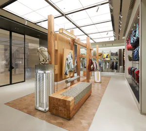 Patagonia 現代零售店內部，大型橡木展示結構、水磨石桌面木長椅、金屬網燈柱，以及在天窗下展示的戶外裝備。