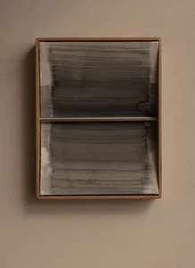 A rectangular wall-mounted artwork with a light oak wooden frame containing two panels of sheer grey fabric with horizontal brushstroke-like patterns and a horizontal metal bar dividing the upper and lower sections, hanging on a textured beige wall.