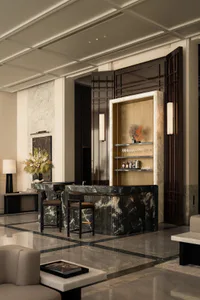 Elegant hotel lobby interior with a curved green marble reception desk, two bar stools, dark wood paneling, and a built-in back bar with glassware and decorative coral.