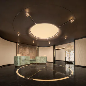 Luxurious hotel lobby featuring a curved green marble reception desk, dark reflective marble floor with gold inlay, and a dramatic circular ceiling fixture with integrated lighting and crystal accents.