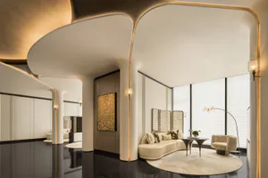 Modern luxury living room featuring dramatic curved white plaster ceiling with integrated gold lighting, glossy black floor, cream curved sofa, and large windows with blinds.